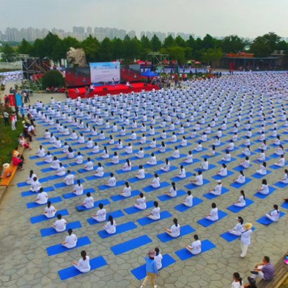 Aerial view of a large outdoor yoga session on blue mats